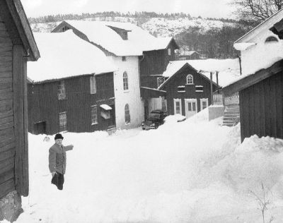 Man stående på snöig gård mellan träbyggnader
Nyckelord: Kvarn