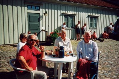 4 personer sittande vid trädgårdsbord på kullerstensgård
Nyckelord: Bord
