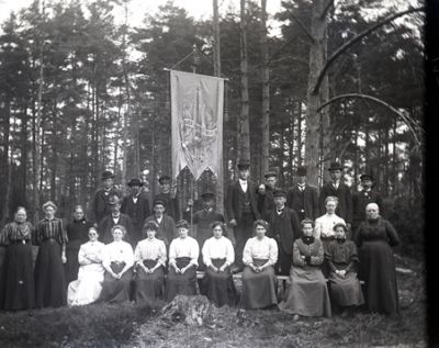 En grupp män och kvinnor samlade runt ett standar
Nyckelord: Standar Dräkt