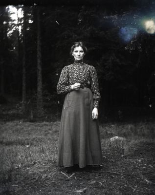 Kvinna stående i skogsglänta
Nyckelord: Dräkt