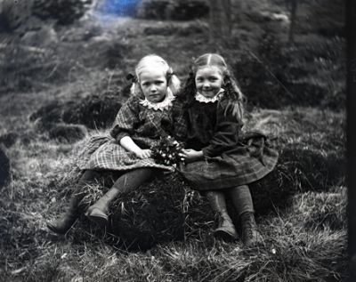 2 flickor med blombukett sittande i naturen
