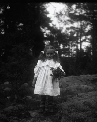 Flicka med blombukett stående i naturen
Nyckelord: Dräkt
