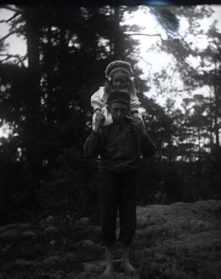 Pojke med liten flicka på axlarna
Nyckelord: Dräkt