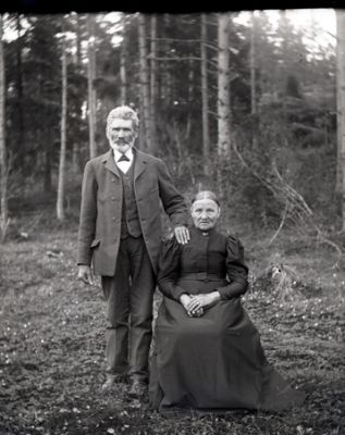 Stående man och sittande kvinna i skogsbryn
Nyckelord: Dräkt