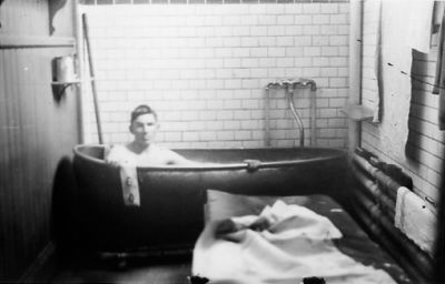 Man sittande i badkar.
