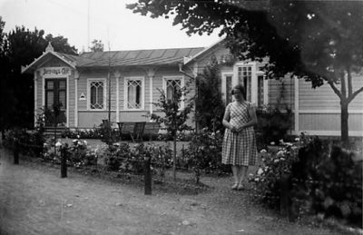 Kvinna stående framför byggnad.
