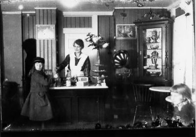 Kvinna bakom disken expedierar 2 flickor.
Nyckelord: Trattgrammofon