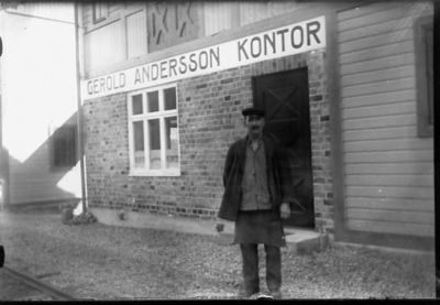 Man stående framför byggnad.
Nyckelord: Magasin Skylt