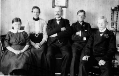 Familj sittande i rum.
