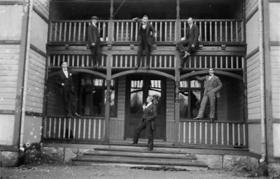 6 män klättrande på veranda.
