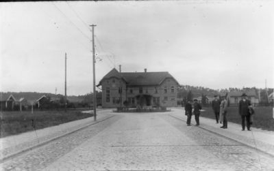 5 män stående på gatan framför byggnad..
