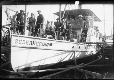 Ett antal personer stående på båt som ligger i torrdocka.
