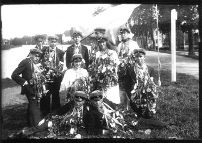 8 män och 3 kvinnor poserande med blommor kring halsen och examensmössor på huvudet.
Nyckelord: Dräkt Blommor