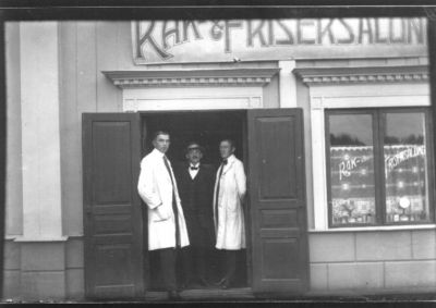 3 män stående i dörröppning.
Nyckelord: Frisersalong Frisör