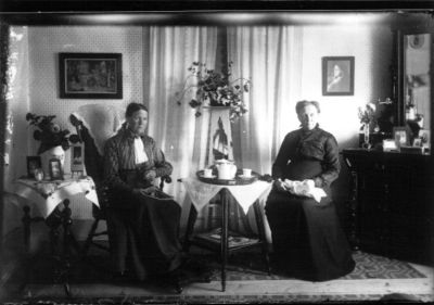 2 kvinnor sittande i rum vid kaffebord.
Nyckelord: Tavla Kaffe Spegel