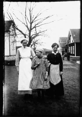 3 kvinnor stående framför byggnader.
