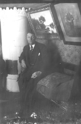 Man sittande i rum.
Nyckelord: Kakelugn Tavla