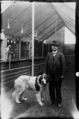 Man stående med hund och papegoja sittande på pinne.
Nyckelord: Hund Papegoja