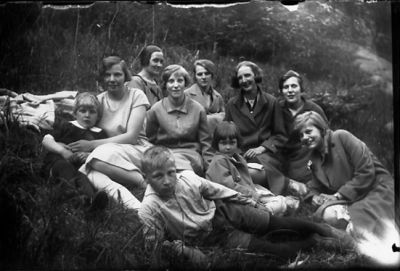 7 kvinnor, 2 pojkar och 1 flicka sittande i skogsbacke.
Nyckelord: Skogsbacke