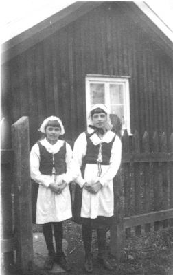 2 flickor stående i grindhål.
Nyckelord: Staket Grindhål Bostad Dräkt