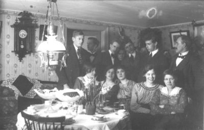 Ett antal personer samlade vid ett kaffebord i rum.
Nyckelord: Kaffe Lampa Klocka