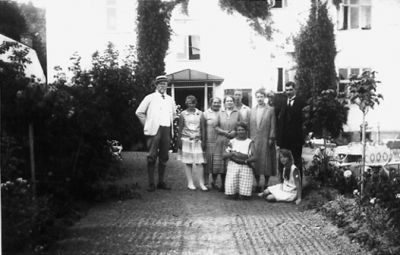 3 män och 4 kvinnor stående och kvinna och flicka sittande på grusgång.
Nyckelord: Grusgång