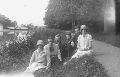 3 män och 3 kvinnor sittande intill vattendrag.
Nyckelord: Stig