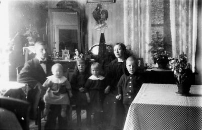 Man, kvinna och 4 barn sittande i rum.
Nyckelord: Fönster Gardin Spegel