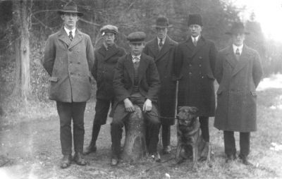 5 män stående och 1 man sittande på pollare med hund vid sidan.
Nyckelord: Hund Pollare