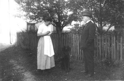 Man, kvinna och hund stående framför staket.
Nyckelord: Hund Staket Trädgård