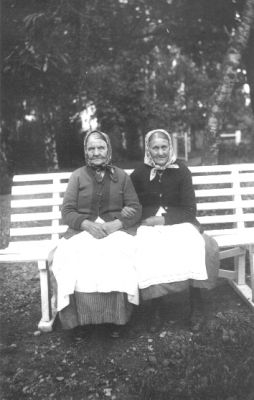 2 kvinnor sittande på parkbänk.
Nyckelord: Parkbänk Träd Dräkt