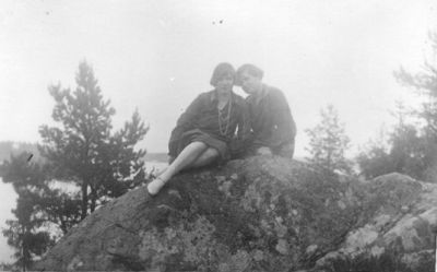 2 kvinnor sittande på berg med vatten i bakgrunden.
