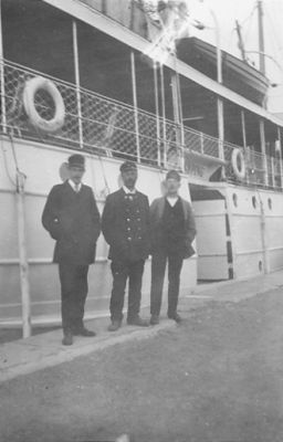 3 män stående framför båt.
Keywords: Kaj