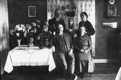 Man och kvinna sittande och man och kvinna stående i rum.
Nyckelord: Blommor Gardin Klocka