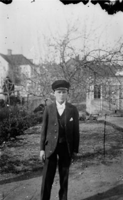 Pojke stående i trädgård.
Nyckelord: Trädgård Bostad