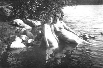 2 kvinnor sittande i vatten.
Nyckelord: Baddräkt