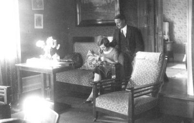 Man stående och kvinna sittande i rum.
Nyckelord: Tavla