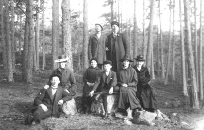 8 personer stående eller sittande i skogsbacke.
Nyckelord: Skogsbacke Skog