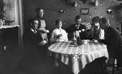 3 män, 2 kvinnor sittande och 1 kvinna stående vid kaffebord.
Nyckelord: Kaffe Duk Tapet