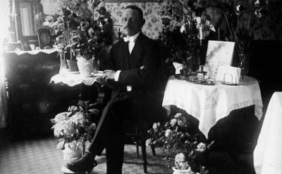 Man sittande i rum med blommor.
Nyckelord: Födelsedag Blommor