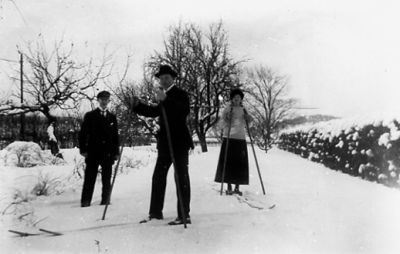 Man och kvinna stående på skidor i snön och man stående utan skidor.
Nyckelord: Vinter