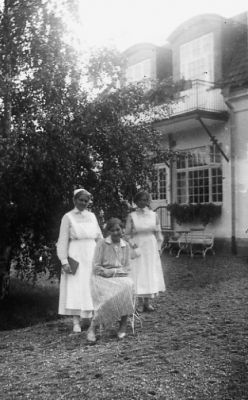 2 kvinnor stående och 1 sittande framför byggnad.
Nyckelord: Byggnad Uniform