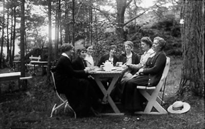 7 kvinnor sittande vid trädgårdsbord med kaffe.
Nyckelord: Trädgårdsmöbel Kaffe Servering