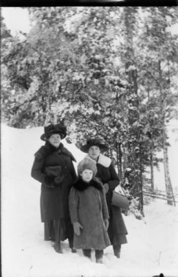 2 kvinnor och 1 flicka stående i snön i skogsbacke.
Nyckelord: Skogsbacke Vinter