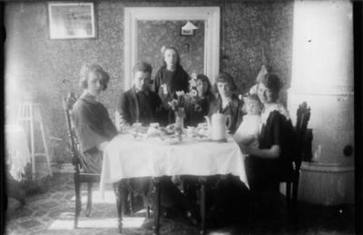Man, 5 kvinnor och 1 flicka runt ett kaffebord.
Nyckelord: Kaffe Kakelugn