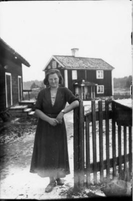 Kvinna stående vid staket.
Nyckelord: Staket