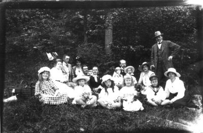 Ett antal personer sittande i skogsbacke.
Nyckelord: Picnickorg