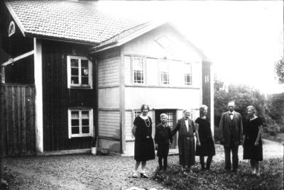 Man, 3 kvinnor och 1 pojke stående framför byggnad.
