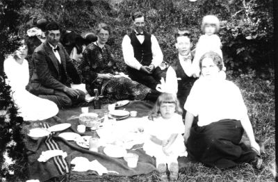 3 män, 3 kvinnor och 2 flickor sittande runt picnicfilt.
Nyckelord: Filt Picnic Flaska