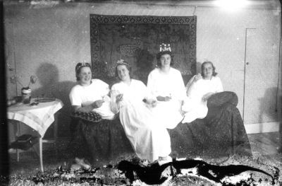 Lucia och 3 tärnor sittande i rum.
Nyckelord: Lucia Väggbonad